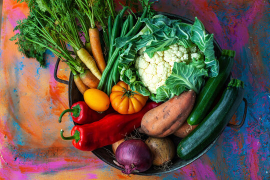 Assorted fresh garden vegetables in bowl with colorful background