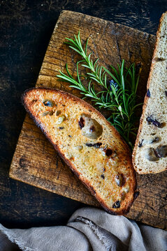 Toasted Sourdough olive bread slices on cutting board with rosemary