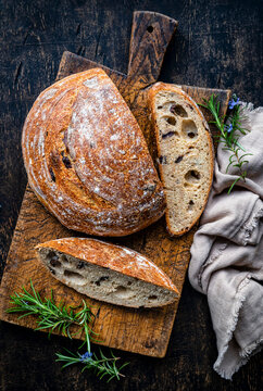 Sourdough olive bread sliced on cutting board with rosemary
