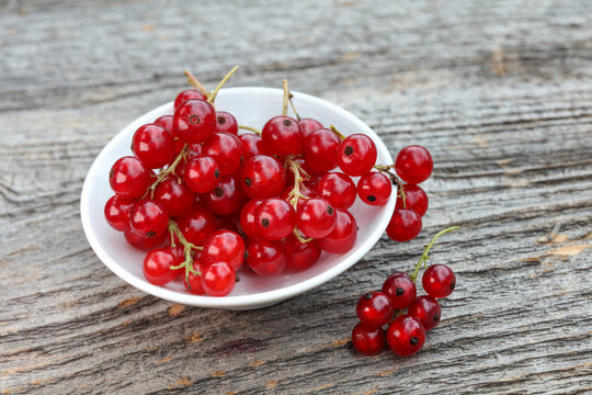 Red Currants in small white bowl on wooden surface