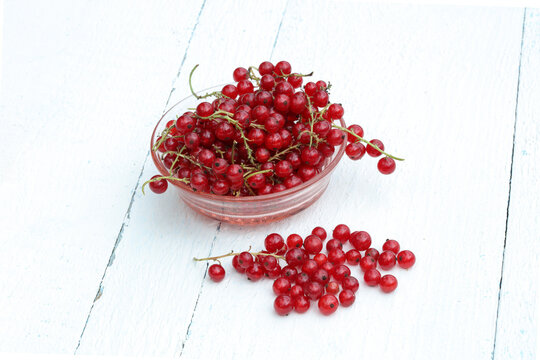 Red Currants in a glass bowl on white wooden surface