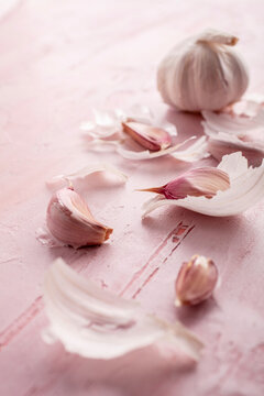 Fresh Garlic cloves and bulb with skins on pink textured surface