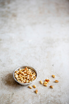 Roasted pine nuts in bowl on gray surface