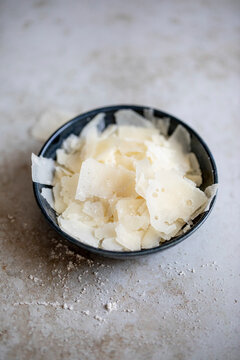 Freshly shaved parmesan cheese in small black bowl