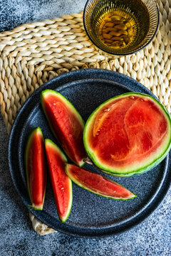 Ripe watermelon slices on dark plate with glass drink on table