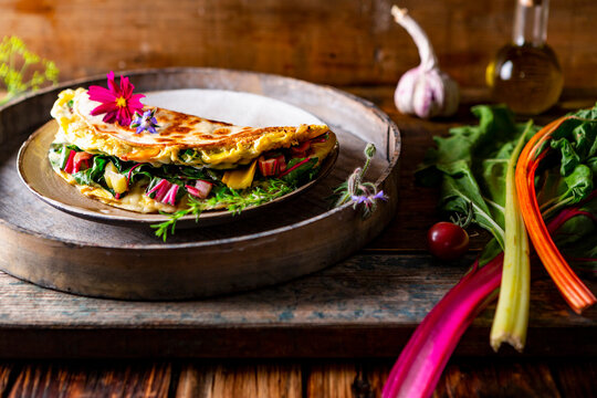Swiss chard egg tortilla with edible flowers on rustic wooden table