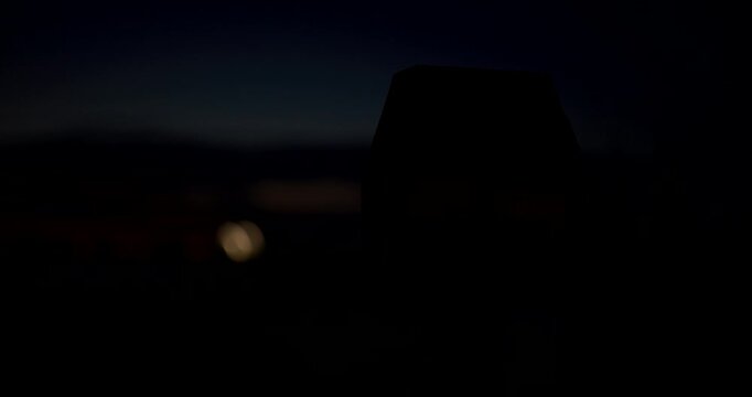 Orange warning light illuminated at dusk with a dramatic dark background and soft distant bokeh. Emergency signal, safety, hazard awareness, transportation and industrial security concept. 4K.