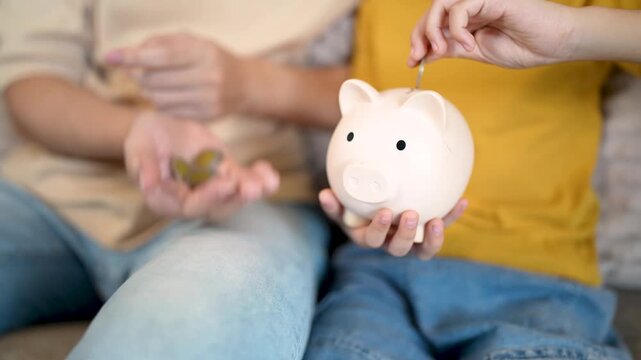 Adult helps child learn to save money in a piggy bank