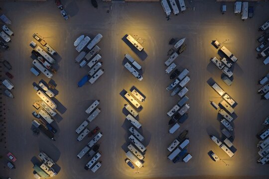 Aerial view of an RV storage lot at night with rows of parked recreational vehicles illuminated by overhead lights in Greeley, Colorado, United States.