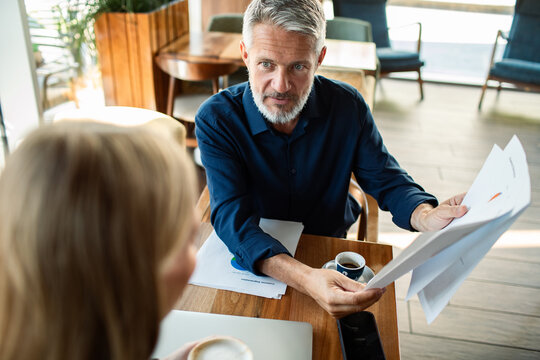 Older man showing report to colleague in cafe