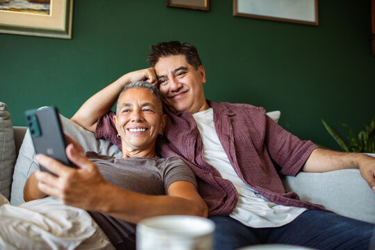 Smiling couple of men taking a selfie on the sofa
