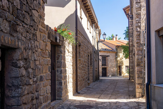 Narrow cobblestone street flanked by traditional stone and rustic masonry facades.