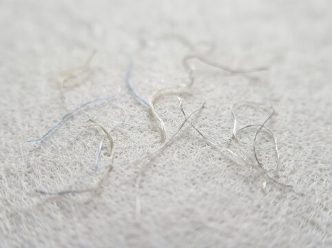 Microplastic fibers on a white textile surface under macro lens