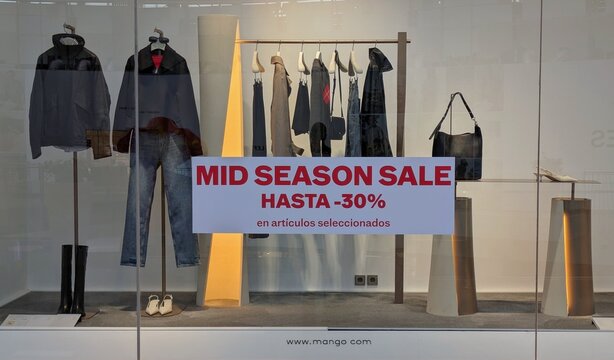 Moda de oto&ntilde;o. Cartel Mid Season Sale -30% en escaparate con perchero con ropa femenina, de una tienda de ropa Mango en Madrid, Espa&ntilde;a, 7 de octubre de 2026