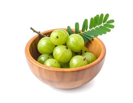 Wooden bowl of green amla fruit on white background