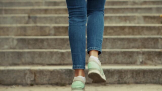 Person Walking Up Concrete Stairs Wearing Jeans And Sneakers 