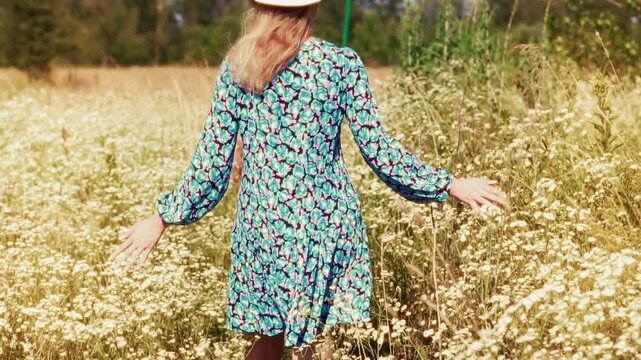 Woman Walking Through Blooming Wildflower Field With Outstretched Arms During Summer Day