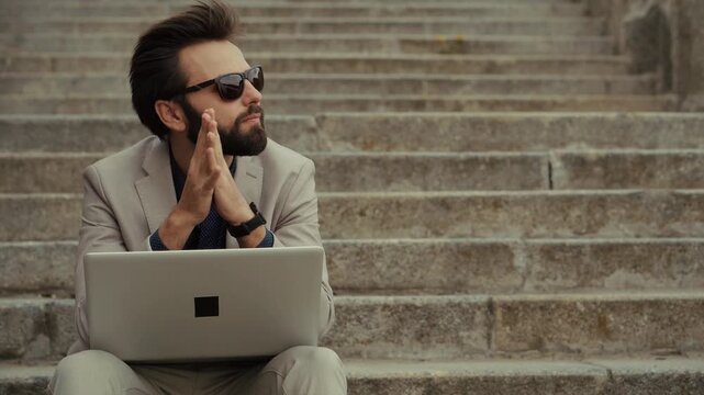 Businessman Working On Laptop While Sitting On Stone Stairs Outdoors With Thoughtful Expression