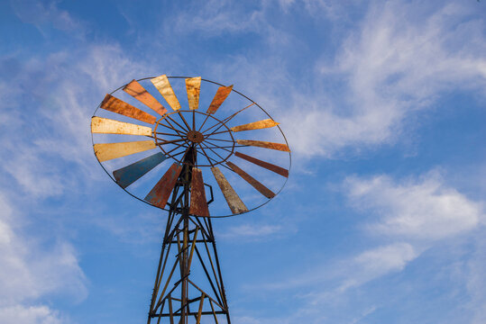 An old windmill on a blue sky background with white clouds.
