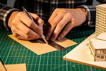 Fototapeta premium Hands cutting card with a scalpel against a steel rule