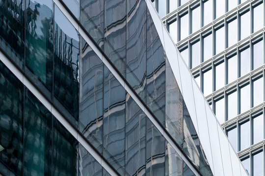 Reflective glass facades with diagonal structure and layered windows forming abstract architecture across modern office building surfaces