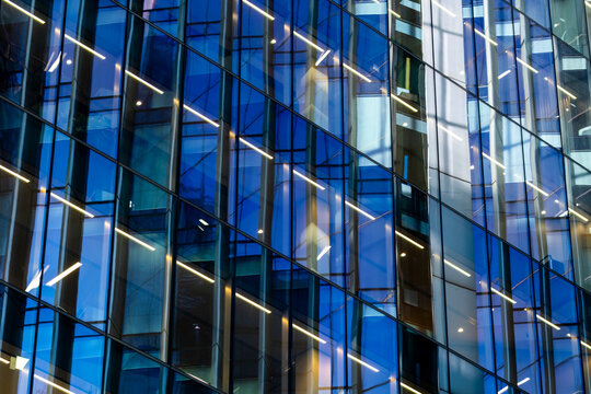 Blue glass facade with illuminated lines and reflective windows creating abstract modern architecture in a geometric exterior closeup