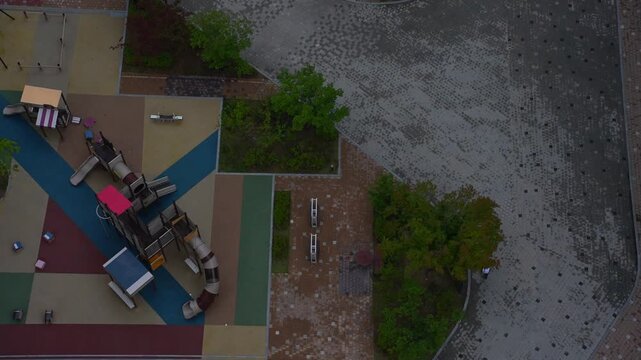Person Walking Past Apartment Playground on Early Morning Commute to Work 