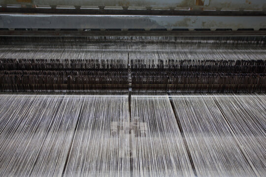 An industrial weaving loom runs at high speed.