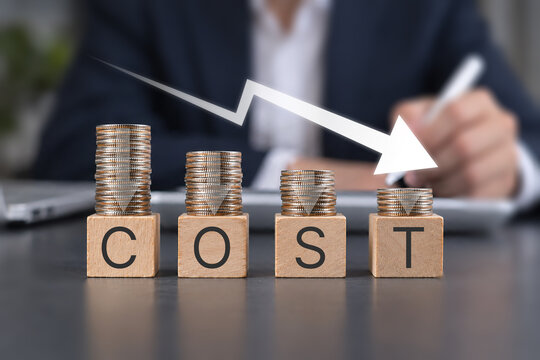 Cost reduction concept. Cost wording on decreasing coins stacking with the down arrow. Businessman working on company cost saving. Cost Management, Economy recession, low budget, Effective business, 