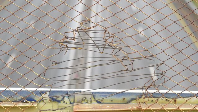 Rusted chain-link fence with tangled wires and deteriorating structure