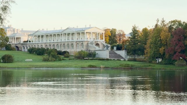 The majestic Cameron Gallery stands above a calm lake in autumn. This pan shot brings a peaceful and romantic mood. Experience Catherine Park, Pushkin, Saint Petersburg.