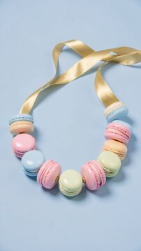 Colorful macaron necklace with ribbon on a blue background  