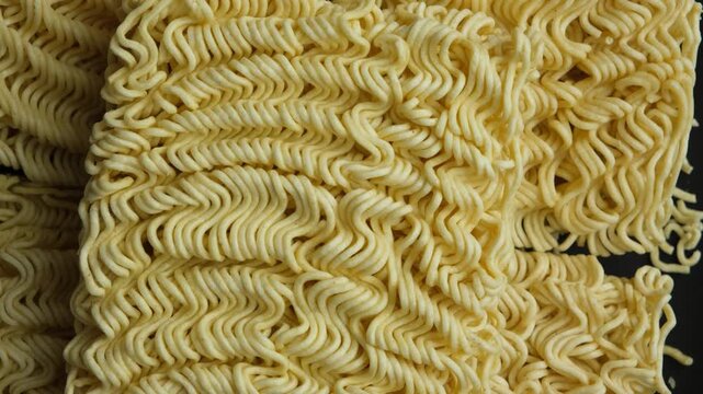 Top view of raw instant ramen noodle blocks slowly rotating close up