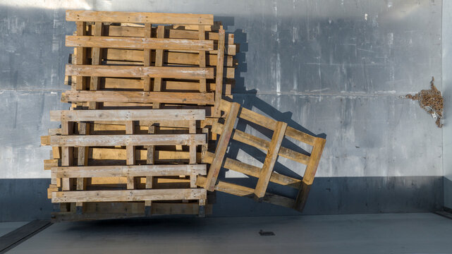 Top view of a stack of wooden pallets lying on a gray metal surface. Zenithal shot.
