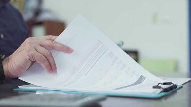 Auditor conducts financial audit review procedures, examining audit paper report verifying audit statement data beside mobile phone.