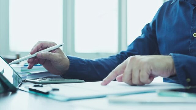 Accountant conducts financial audit duties, reviewing audit sheets beside digital tablet screens where internal audit data verifies balance statements accurately.