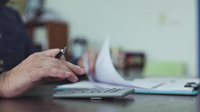 Accountant performs accounting duties calculating monthly expenses, managing finance records as accounting review proceeds alongside critical finance reporting on office paperwork.