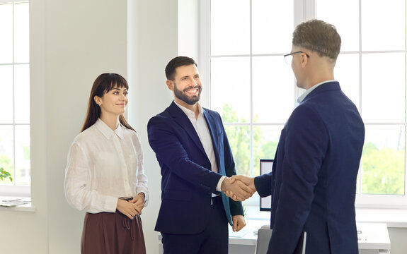 Handshake between businesspeople partners finalizing agreement. Smiling colleagues close a new deal in a bright office after a productive meeting. Teamwork and negotiation drive business success.