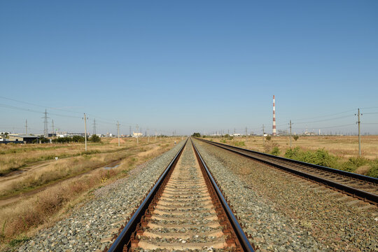Railway tracks stretching straight into the distance under a clear blue sky