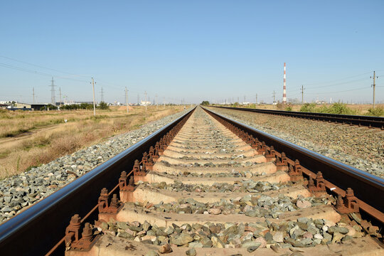 Railroad tracks leading toward the horizon with power lines visible in the distance