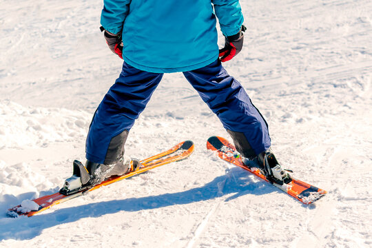 Kid boy legs riding downhill,learn skiing in mountains alpine winter resort.little child enjoy extreme sport activities recreation,family luxury vacation