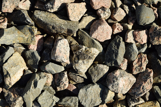 Close-up texture of rough grey and brown stones used as railway ballast