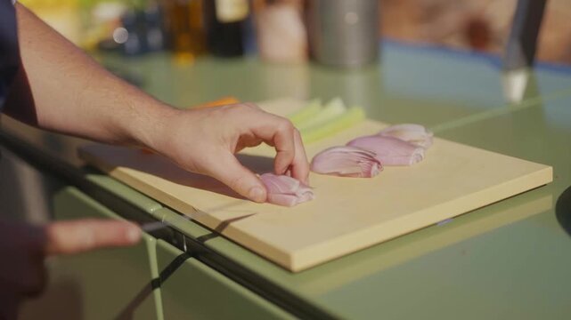 Chef prepares sliced meat on a wooden cutting board outdoors