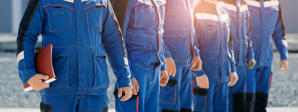 Team of industrial electricians engineers in blue work uniforms standing in line for crew roster and workplace safety banner