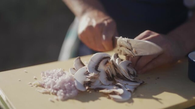 Sliced mushrooms and onions are prepped on a wooden cutting board