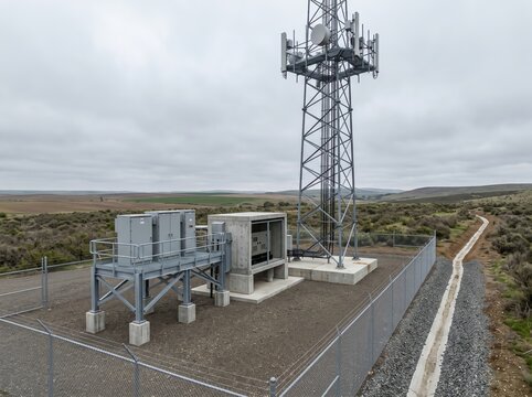Cellular tower and equipment enclosure on fenced rural plain