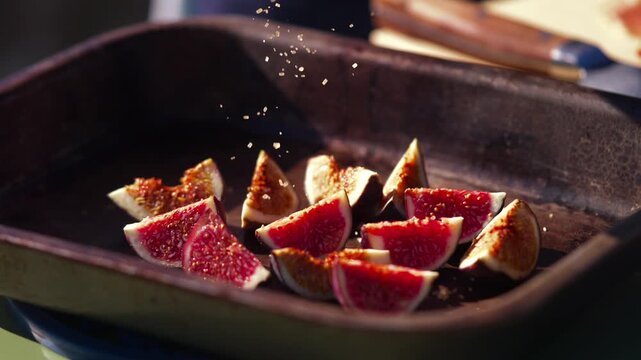 Fresh figs are sprinkled with seasoning in a rustic outdoor kitchen