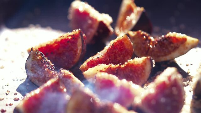 Grilled fig halves with sugar smoke on a metal grill plate