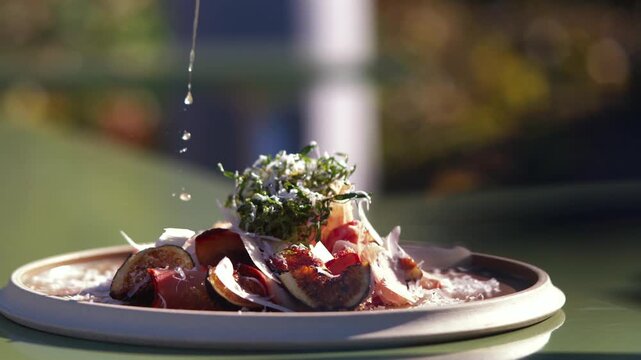 Gourmet fig and prosciutto dish with fresh herbs on a plate