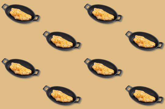Repeating pattern of baked ocean perch fillets in black oval handled dishes arranged on a warm golden background